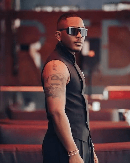 Nollywood actor Timini Egbuson wearing sunglasses and a sleeveless black outfit.